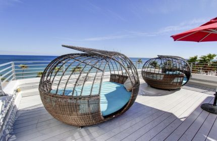Gay-friendly hotel rooftop with unique lounge chairs offering ocean views. Perfect for snoozing in style. A luxurious, relaxing vacation spot.