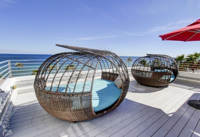 Gay-friendly hotel rooftop with unique lounge chairs offering ocean views. Perfect for snoozing in style. A luxurious, relaxing vacation spot.