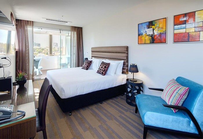 Hotel 57 gay-friendly room. Modern interior with a bed, chair, desk, and balcony. Colorful paintings add a vibrant touch to this stylish space.