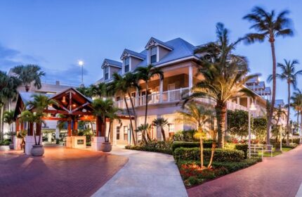 Opal Key Resort and Marina, a gay-friendly hotel. Exterior view of the resort at dusk with palm trees and well-lit walkways.