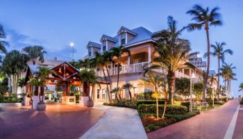 Opal Key Resort and Marina, a gay-friendly hotel. Exterior view of the resort at dusk with palm trees and well-lit walkways.