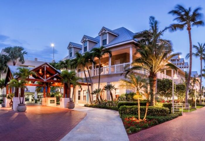 Opal Key Resort and Marina, a gay-friendly hotel. Exterior view of the resort at dusk with palm trees and well-lit walkways.