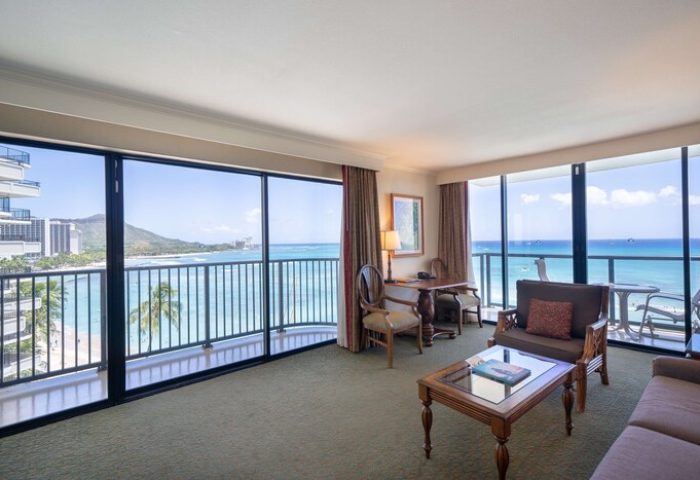Outrigger Waikiki Beach Resort gay-friendly hotel suite. Ocean view from balcony, desk, and seating area. Perfect for gay men's travel to Hawaii.