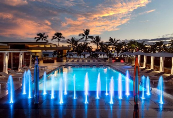 Waikiki Beach Marriott Resort & Spa pool at sunset. Gay-friendly hotel with fountains, palm trees, lounge chairs, and cabanas. Perfect for gay travel.