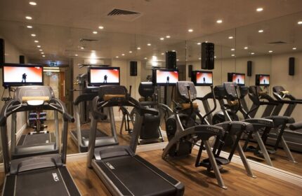 Gym at The Bank Hotel Istanbul, a Design Hotel. Treadmills and elliptical machines with TVs. Gay-friendly hotel fitness center.