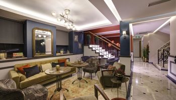 The Fox Hotel's stylish lobby. Gay-friendly hotel with seating, stairs, and a mirror. A comfortable space for gay men to relax and socialize.