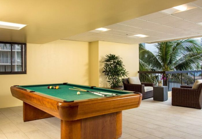 Aston Waikiki Beach Tower gay-friendly hotel: Billiard table and outdoor seating area with palm trees. Relaxing recreation for gay travelers.