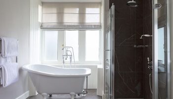 Bathroom at SCHLOSS Roxburghe Hotel, a gay-friendly hotel. Features a clawfoot tub, window, and shower. Gay travel advice for discerning men.