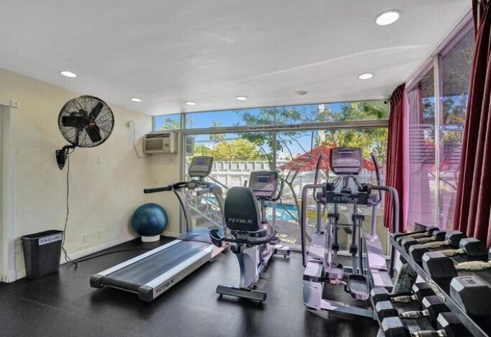 Gym at The Grand Resort and Spa, an all-male spa resort. Gay-friendly hotel with treadmill, elliptical, and weights. Pool view from fitness area.