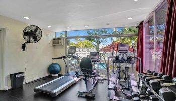 Gym at The Grand Resort and Spa, an all-male spa resort. Gay-friendly hotel with treadmill, elliptical, and weights. Pool view from fitness area.