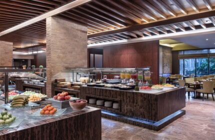 Sofitel Dubai The Palm Resort breakfast buffet. Gay-friendly hotel with fresh fruit, juices, and pastries. Dining area with tables and chairs.