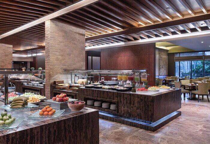 Sofitel Dubai The Palm Resort breakfast buffet. Gay-friendly hotel with fresh fruit, juices, and pastries. Dining area with tables and chairs.