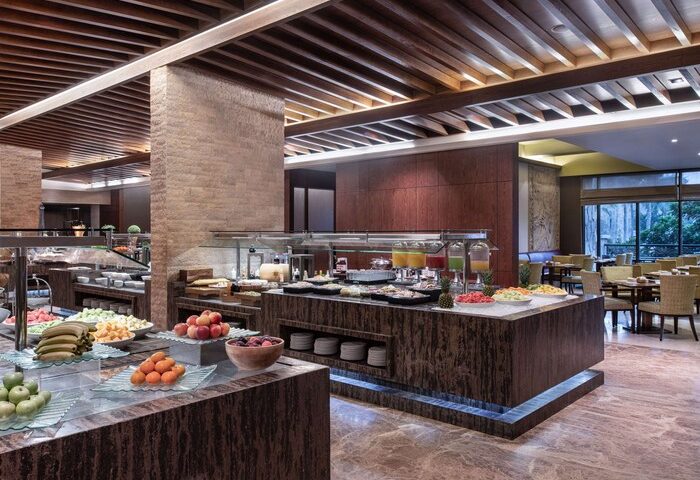 Sofitel Dubai The Palm Resort breakfast buffet. Gay-friendly hotel with fresh fruit, juices, and pastries. Dining area with tables and chairs.