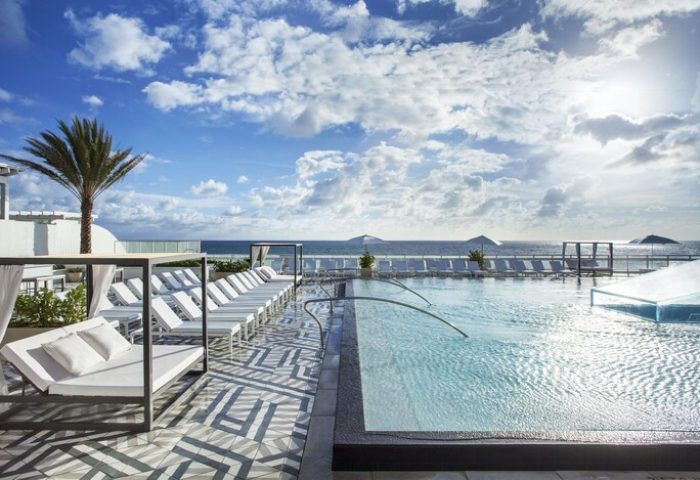 W Fort Lauderdale gay-friendly hotel pool view. Oceanfront resort with lounge chairs, cabanas, and palm trees. Perfect for gay travel.