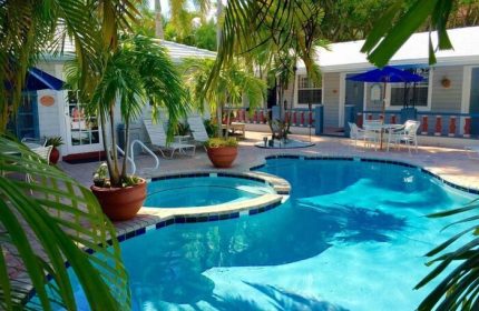 Coral Reef Guesthouse pool and patio. Gay-friendly hotel with tropical plants, lounge chairs, and outdoor dining. A relaxing gay travel destination.