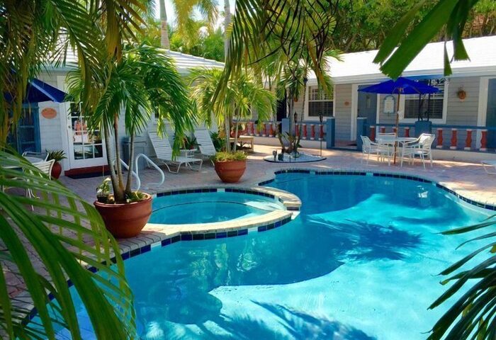Coral Reef Guesthouse pool and patio. Gay-friendly hotel with tropical plants, lounge chairs, and outdoor dining. A relaxing gay travel destination.
