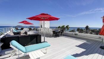 Gay-friendly hotel rooftop deck with red umbrellas, lounge chairs, and ocean view. Perfect for a relaxing vacation. Snooze at this gay hotel!