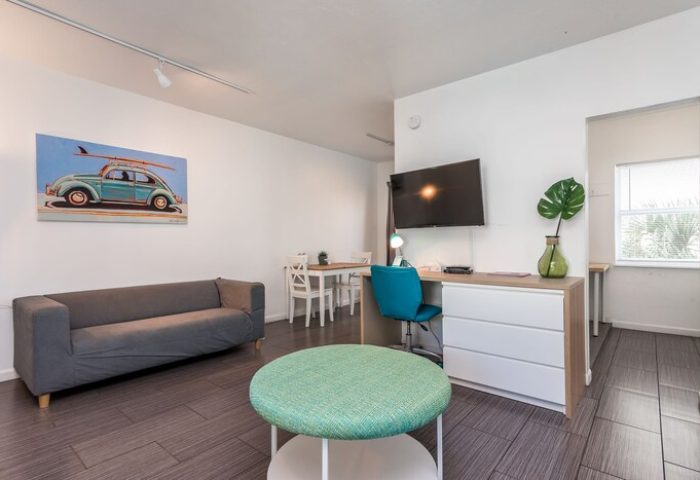 Nobleton Hotel gay-friendly room. Living area with couch, desk, TV, & dining table. Surf art adds a beachy vibe for gay men's travel.
