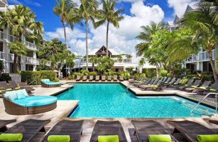 Opal Key Resort pool view. Gay-friendly hotel with palm trees, lounge chairs, and turquoise water. Perfect for LGBTQ+ travel. Key West marina.