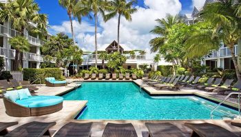 Opal Key Resort pool view. Gay-friendly hotel with palm trees, lounge chairs, and turquoise water. Perfect for LGBTQ+ travel. Key West marina.