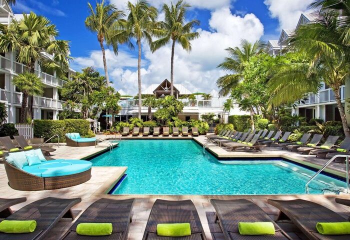 Opal Key Resort pool view. Gay-friendly hotel with palm trees, lounge chairs, and turquoise water. Perfect for LGBTQ+ travel. Key West marina.