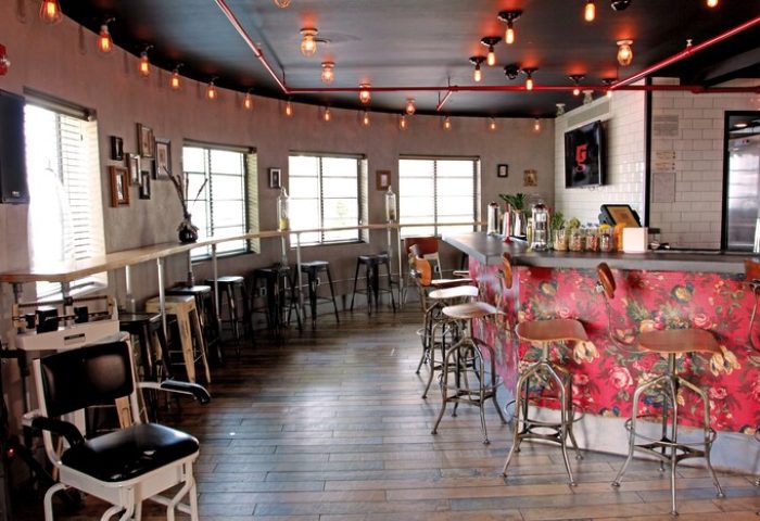 Hotel Gaythering's gay-friendly bar area. All adults welcome. Interior with bar stools, floral bar front, and vintage-style lighting.