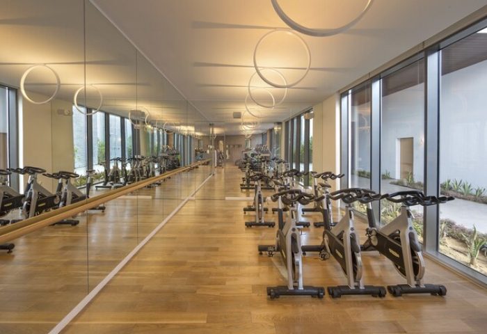Nikki Beach Resort & Spa Dubai gym. Indoor cycling studio with stationary bikes, mirrors, and natural light. Gay-friendly hotel fitness center.