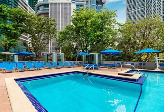 Hyatt Regency Miami gay-friendly hotel pool. Hotel with blue lounge chairs, umbrellas, and cabanas. Great for gay travel to Miami.