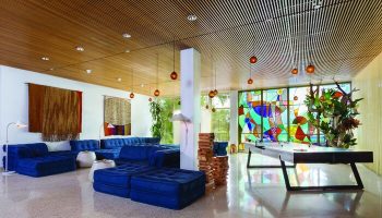 The Standard Miami gay-friendly hotel lobby. Blue sofas, tapestries, and a stained-glass window create a stylish, welcoming atmosphere.