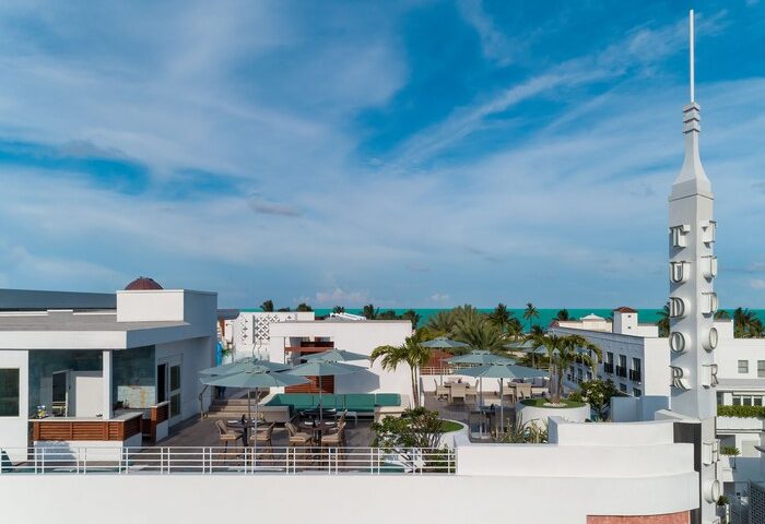 Dream South Beach, a gay-friendly hotel, part of Hyatt. Rooftop view of the Tudor building, palm trees, and ocean. A perfect vacation spot.