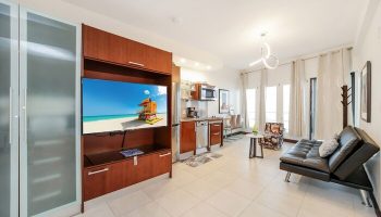 Ocean Drive Suites gay-friendly hotel room interior. Features a TV with a beach scene, kitchenette, and modern decor. Perfect for gay travel.