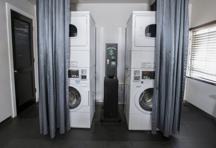 Laundry room at Posh South Beach, a gay-friendly hotel. Stacked washer and dryer units with a payment machine. Convenient amenities for gay travelers.