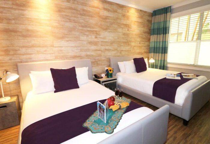 Hotel Shelley room with two beds. Gay-friendly hotel with modern design, wood-look wall, and purple accents. Relaxing travel destination.