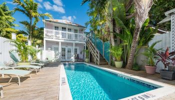 Wicker Guesthouse pool area. Gay-friendly hotel with a pool and lounge chairs. Tropical plants surround the pool. Key West travel.
