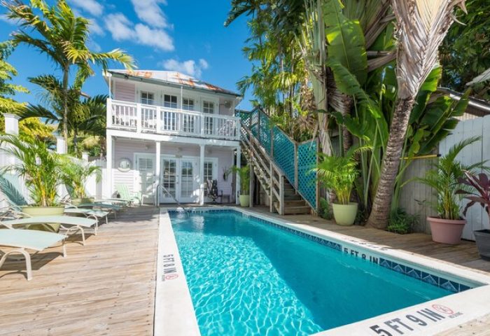 Wicker Guesthouse pool area. Gay-friendly hotel with a pool and lounge chairs. Tropical plants surround the pool. Key West travel.