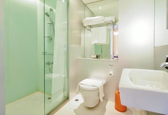 Bathroom at Gay-Friendly 60 West Hotel: Clean, modern design with glass shower, toilet, sink, and towels. Ideal for gay men's travel.