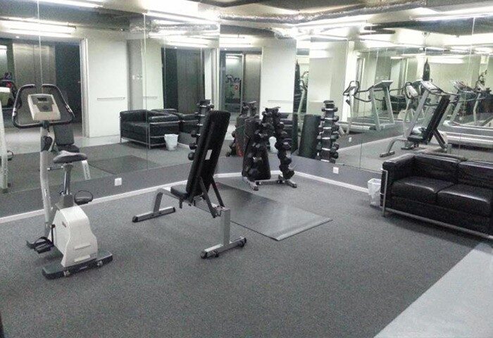 60 West Hotel gym. Gay-friendly hotel fitness center with exercise bike, weight bench, dumbbells, treadmills, and a black leather sofa.