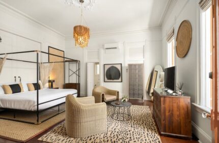 Marrero's Guest Mansion gay-friendly hotel room. Canopy bed, rattan chairs, and animal print rug. Stylish gay travel lodging.