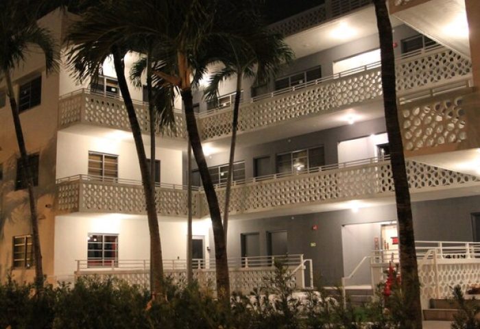 Hotel Gaythering, a gay-friendly hotel welcoming adults. Night view of the hotel's exterior with palm trees. Miami Beach gay travel.
