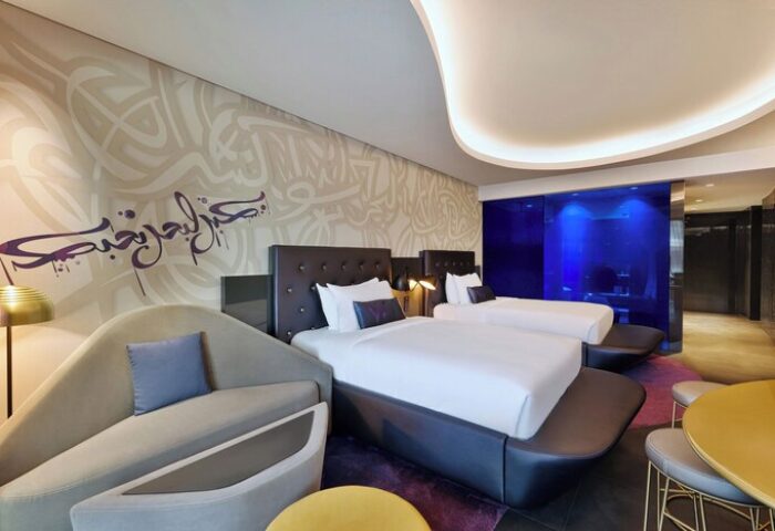 W Dubai - The Palm, gay-friendly hotel room. Two beds, modern design, Arabic calligraphy on the wall. Luxury travel for gay men.