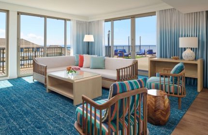 OUTRIGGER Reef Waikiki Beach Resort gay-friendly hotel room. Living area with ocean view, seating, and balcony. Modern, stylish decor.