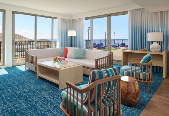 OUTRIGGER Reef Waikiki Beach Resort gay-friendly hotel room. Living area with ocean view, seating, and balcony. Modern, stylish decor.