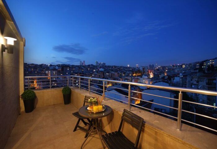 The Fox Hotel's gay-friendly room balcony at night. City view from Istanbul hotel. Table and chairs on the balcony.