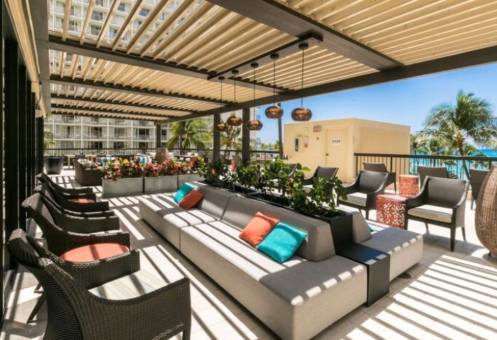 Aston Waikiki Beach Tower's gay-friendly hotel outdoor lounge area. Features stylish seating, plants, and a view of the ocean. Relaxing space.