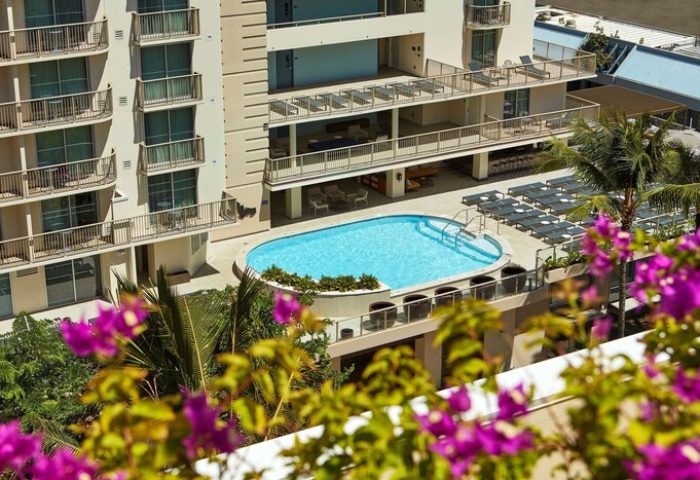 Hilton Garden Inn Waikiki Beach gay-friendly hotel view. Pool, balconies, and lounge chairs. Perfect for gay travel in Waikiki.