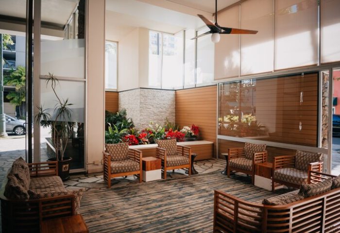 Pacific Monarch Hotel lobby seating area. Gay-friendly hotel with plants, chairs, and a ceiling fan. Relaxing space for gay men's travel.
