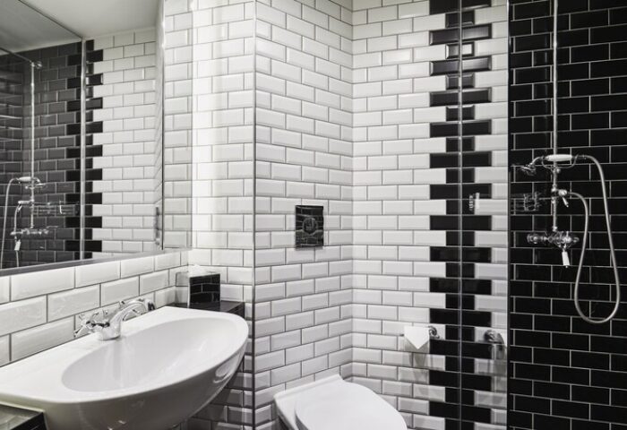 The Hoxton, Holborn gay-friendly hotel bathroom with black & white tiles, sink, toilet, and shower. Modern design for gay men travel advice.
