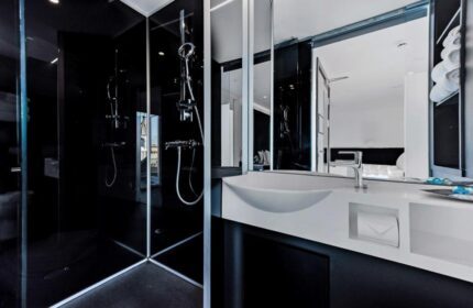 Modern bathroom at The Z Hotel Covent Garden, a gay-friendly hotel. Features a sleek black shower, white sink, and mirrored wall. Ideal for gay travel.