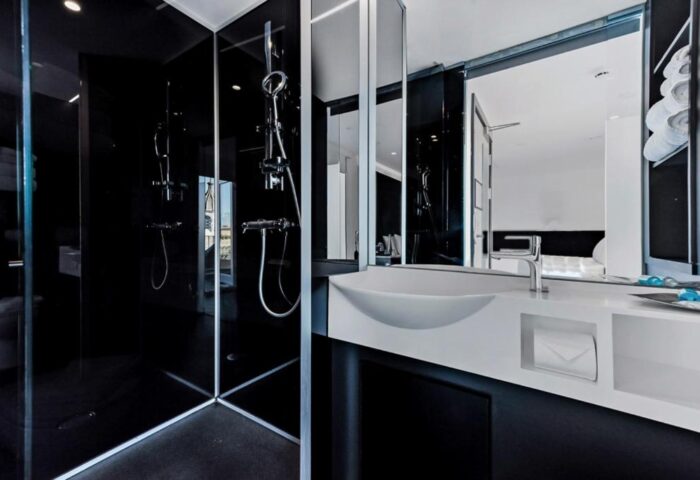 Modern bathroom at The Z Hotel Covent Garden, a gay-friendly hotel. Features a sleek black shower, white sink, and mirrored wall. Ideal for gay travel.