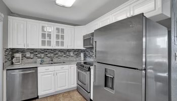 Kitchen at gay-friendly hotel. Stainless steel fridge, oven, dishwasher, and microwave. White cabinets and mosaic backsplash. All-male spa resort.
